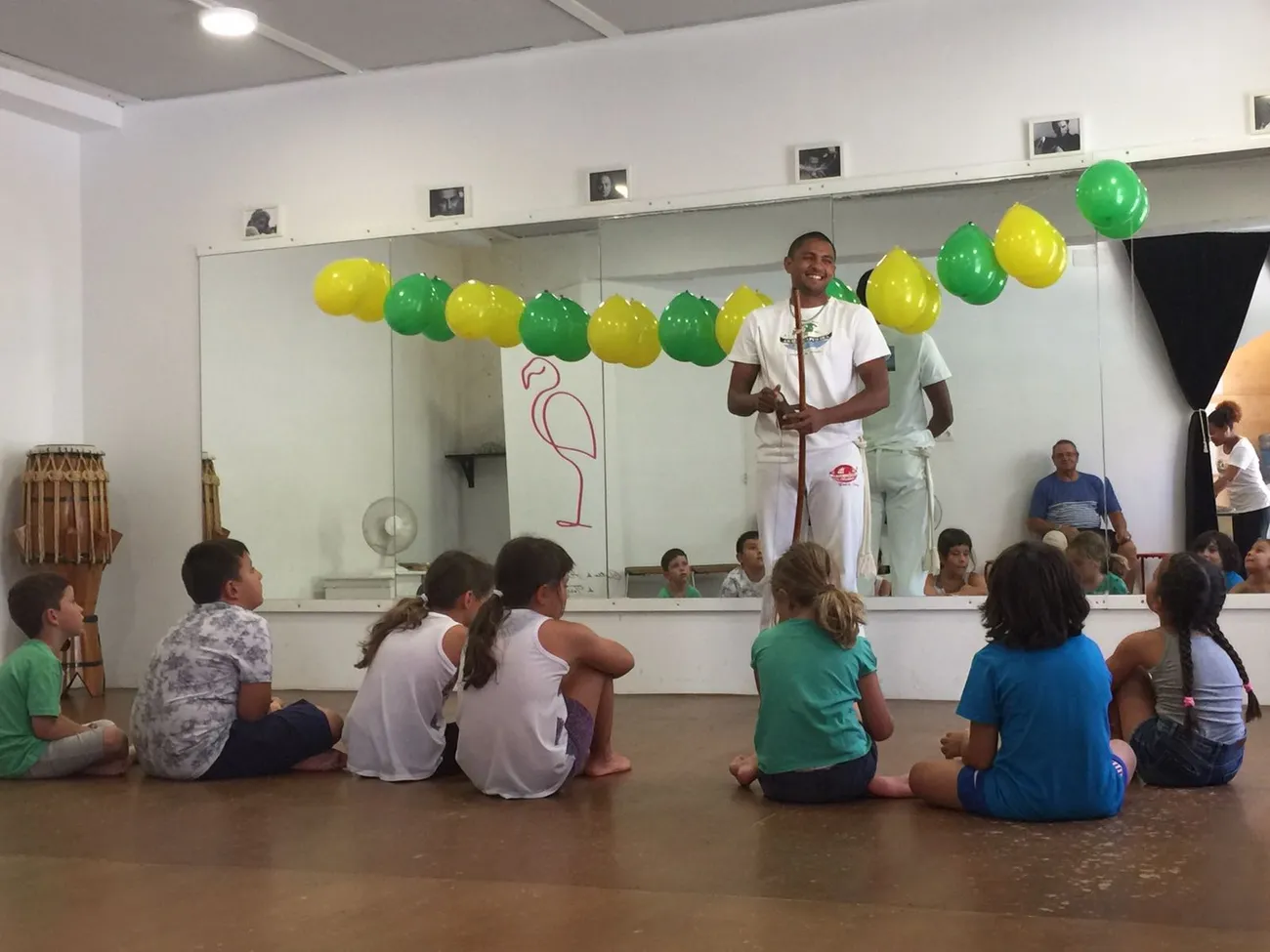 El Profesor Pingo tocando el berimbau mientras un grupo de niños hace la ponte en la sala decorada con globos