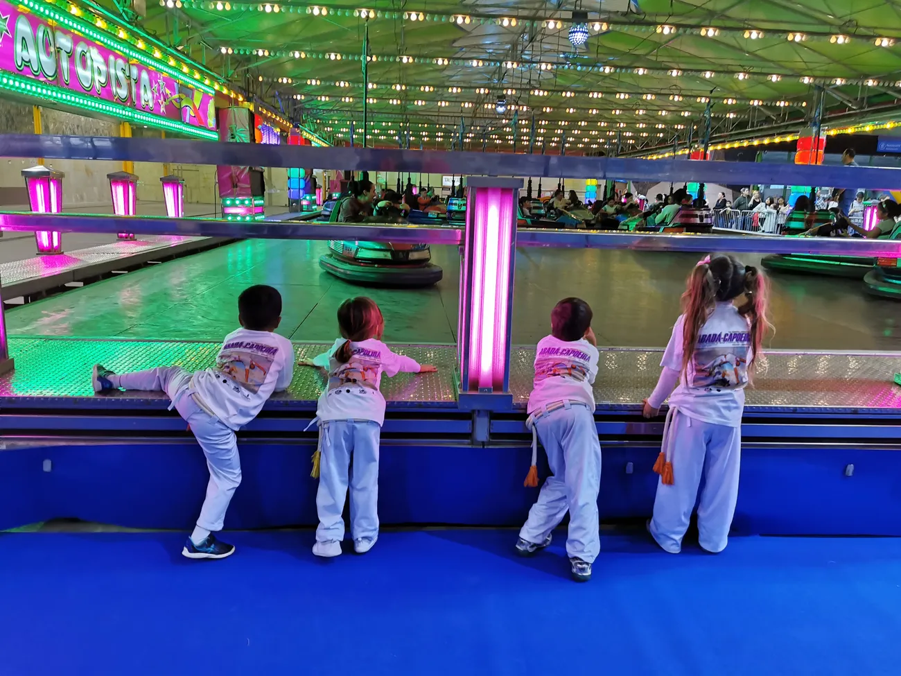 Niños de la escuela con el uniforme blanco en una salida a un parque de atracciones cubierto
