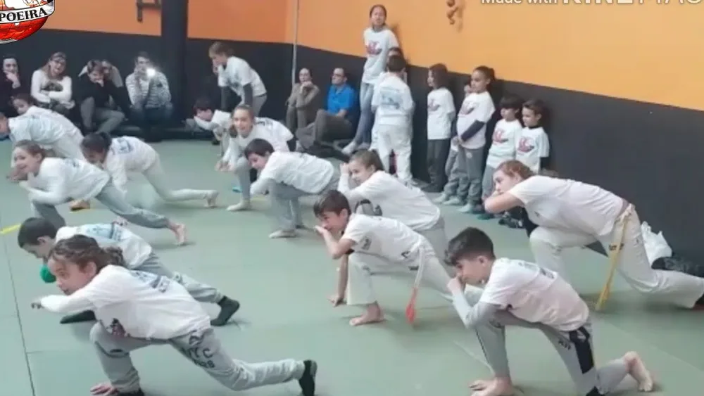 Niños y niñas de la escuela haciendo una secuencia de capoeira en fila durante la clase